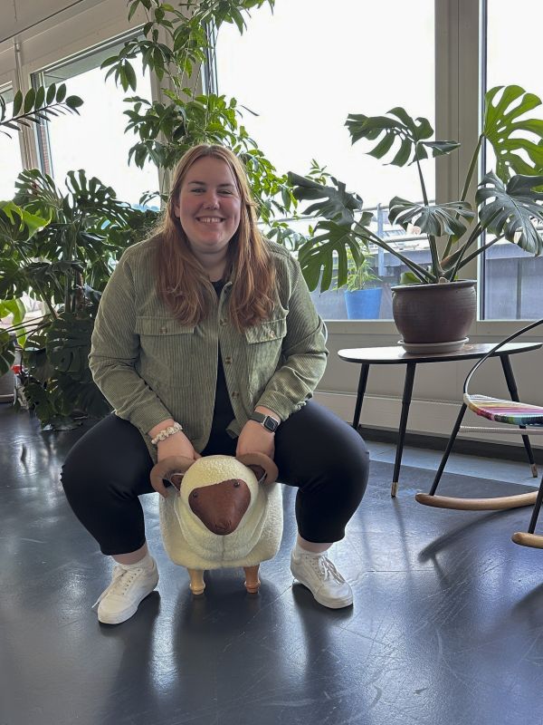 Roberta sitzt auf einem Kinderhocker der aussieht wie ein Schaf